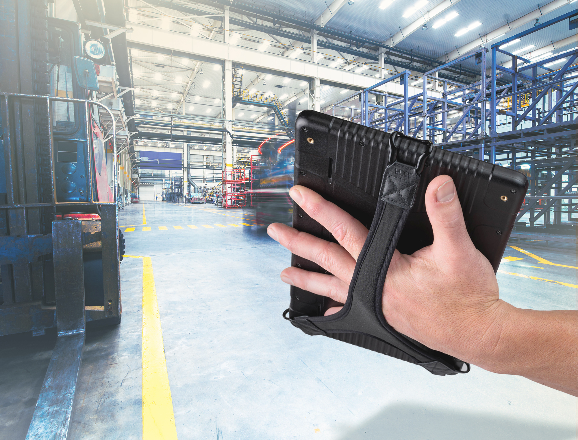 Man using tablet with JACS Solutions accessory strap in warehouse.