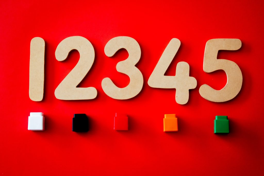 Numbers 1 through 5 on a wall with different colored dry erase caps below