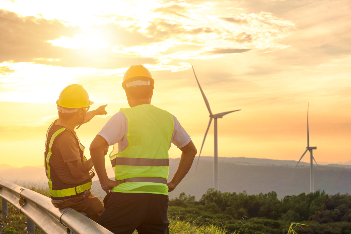 Two engineers overlooking wind turbines