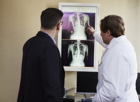 Doctor next to patient reviewing x-ray images of a spinal cord