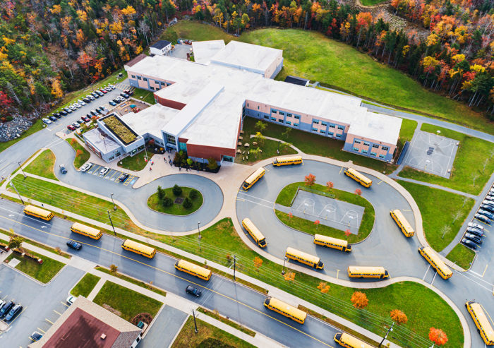 Aerial shot of public elementary school showing buses with wireless tablet lining up to pick up students