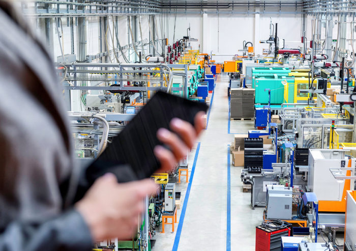 Manager holding tablet while overseeing a production line