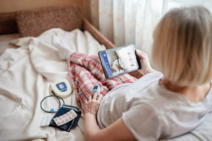 Woman using healthcare tablet for telehealth to share vitals with doctor.