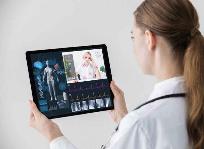 Female doctor with ponytail reviewing medical charts with patient virtually