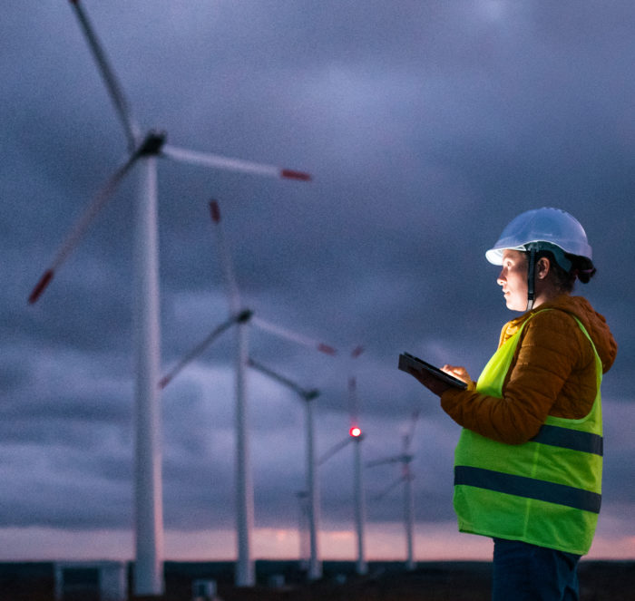 Electricity Maintenance Engineer working on the field with a mobile tablet at a Wind Turbine Power.