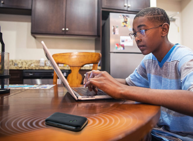 African American student doing schoolwork at home on kitchen table using a TD0301 mobile connectivity modem