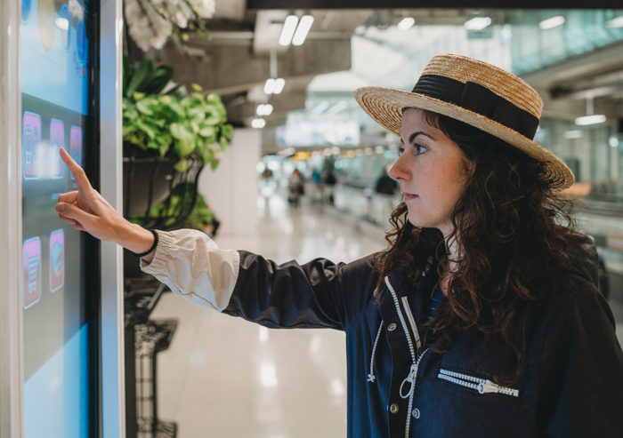 Mall shopper touching large display for wayfinding or self checkout at retail.