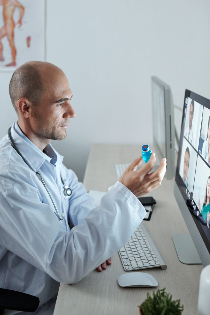 Doctor in office collaborating with healthcare professionals remotely to discuss medications