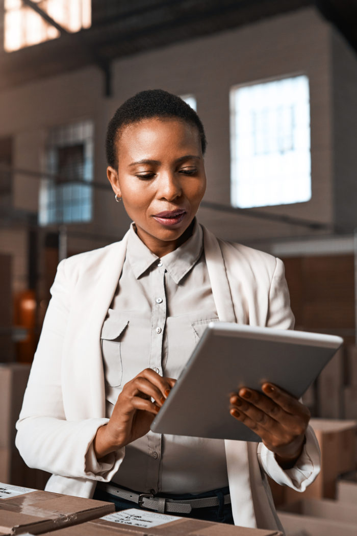 Woman using tablet in retail store to track inventory and online orders.