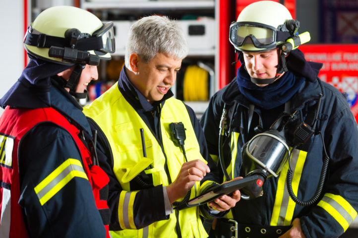 Firefighters discussing analytics in firehouse together on a tablet
