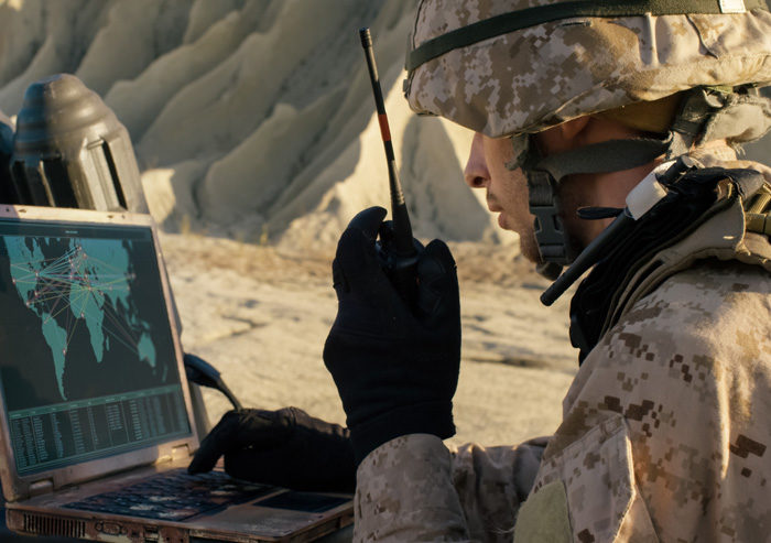 American soldier communicating to base in field using laptop