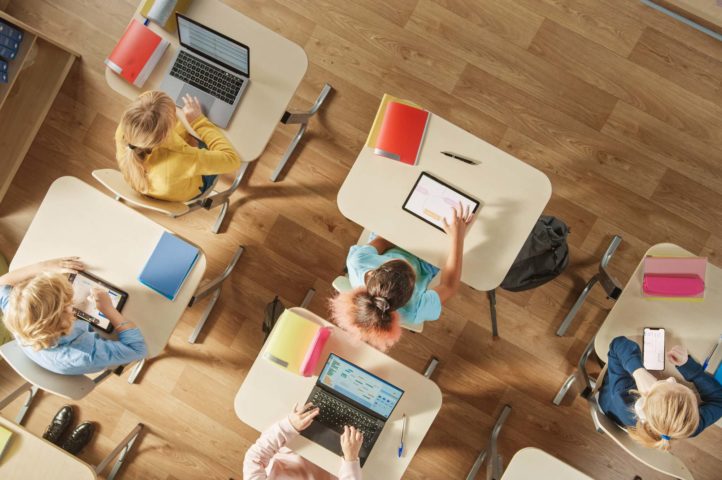 Aerial shot of a classroom, where students are at their desks working on various connected technology devices