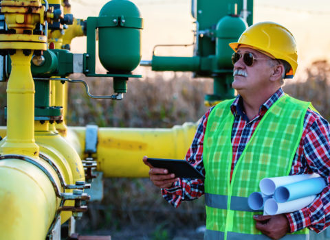 Engineer inspecting a oil and gas production line in the field with a customized tablet